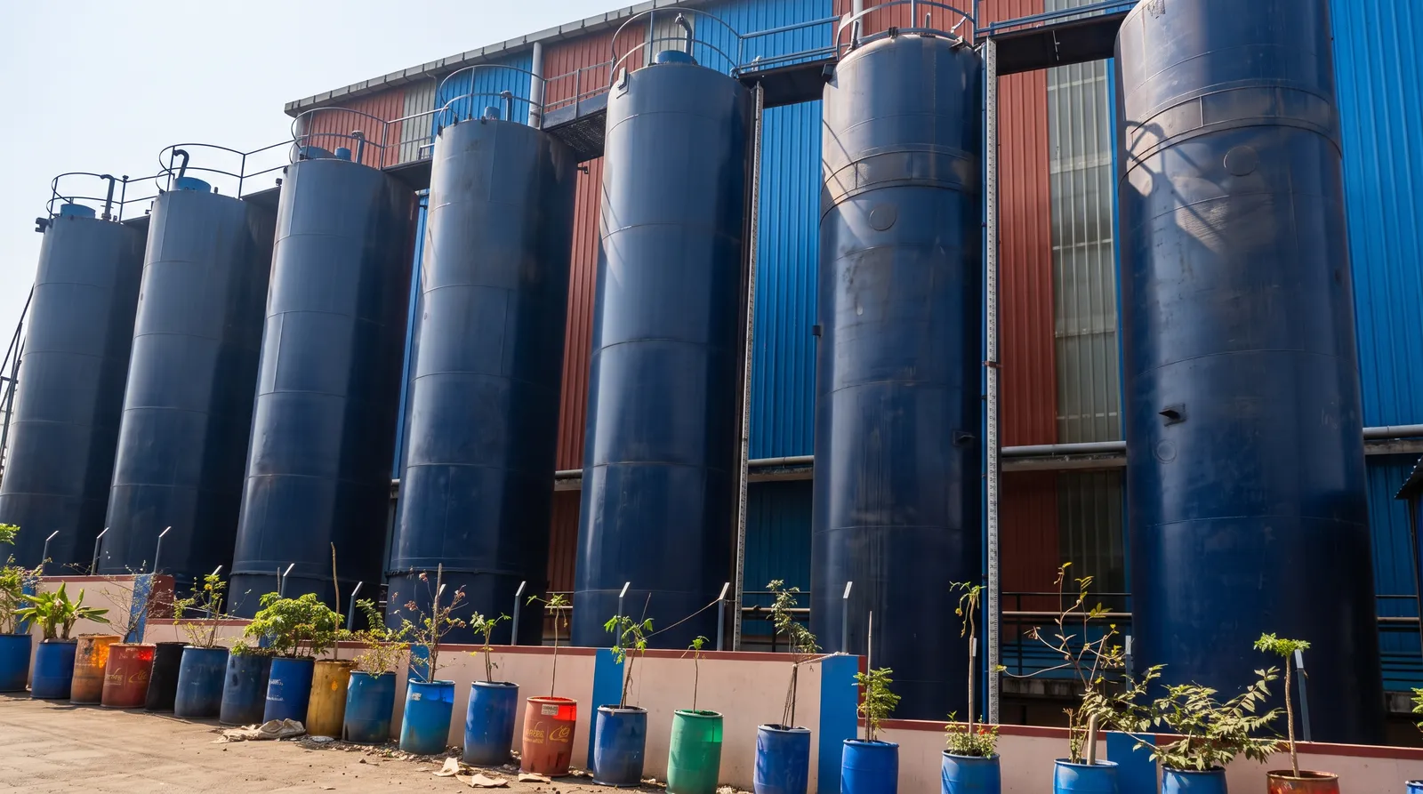Row of blue bulk oil storage tanks at the Shree Mahadev Lubricants factory